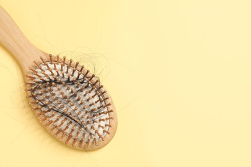 Wooden brush with lost hair on yellow background, top view. Space for text