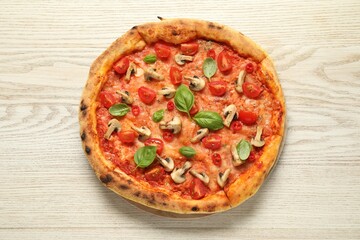 Delicious pizza with tomatoes, mushrooms and basil on wooden table, top view