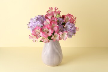 Beautiful alstroemeria flowers in vase on beige background