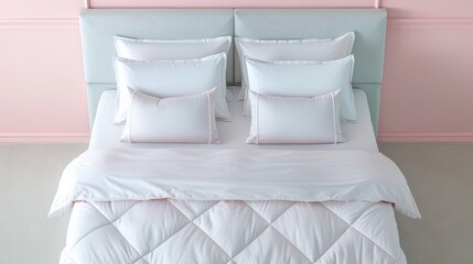 A pristine white bed with a quilted duvet and multiple pillows, against a soft pink wall.