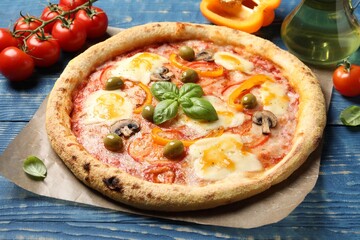 Delicious vegetarian pizza and ingredients on blue wooden table, closeup