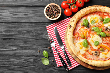 Delicious vegetarian pizza served on black wooden table, top view. Space for text