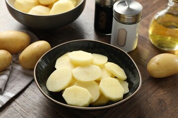 Fresh raw potatoes, spices and oil on wooden table