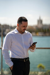 Hombre joven con traje y camisa en sitio lujoso con mar. Business man. Trabajando con tablet y...