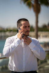 Hombre joven con traje y camisa en sitio lujoso con mar. Business man. Trabajando con tablet y...