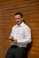 Hombre joven con traje y camisa en sitio lujoso con mar.  Business man. Trabajando con tablet y...