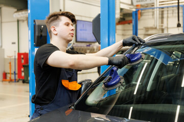 Professional mechanic using suction pads on car windscreen
