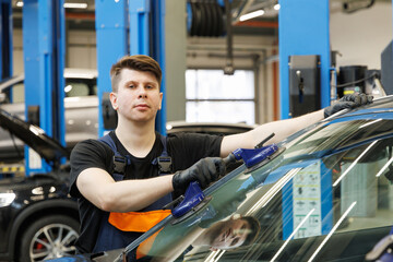 Portrait of a professional mechanic in a car service replacing windshields
