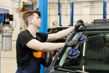 Fototapeta premium Professional mechanic using suction pads on car windscreen