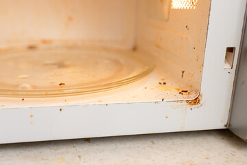 A dirty microwave oven with an open door in need of washing and cleaning