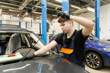 Naklejka premium Automotive glazier removing rubber seal from windscreen