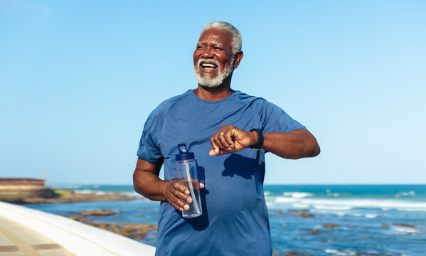 Mature man exercising by the seaside with fitness watch - focus on longevity