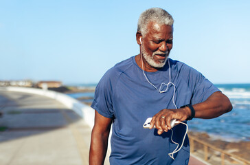 Older man exercising seaside with fitness watch and music