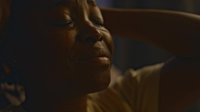 Closeup of young Black woman crying at night while experiencing traumatic memories about sexual assault, being victim of violence