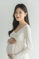 Obraz premium Asian Pregnant Woman in White Long Sleeve Smiling at Camera