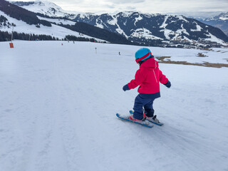 Kid enjoying ski adventure on a sunny winter day do first slide