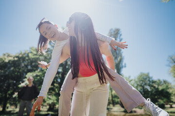 Two young women enjoying a playful piggyback ride in a park on a bright sunny day, embodying joy...