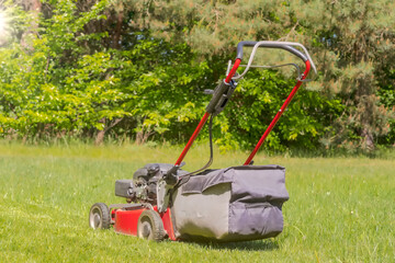 A petrol lawn mower mowing the grass. A petrol lawnmower with powered rear wheels cutting grass on a large home lawn.
