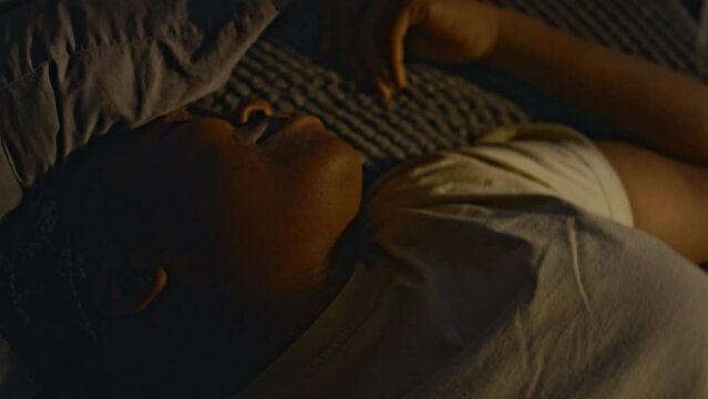 Closeup of young Black woman with tears on cheeks having troubled sleep, turning over in bed and recalling awful events in nightmares. Life after traumatic events, having ptsd