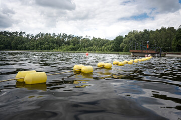 Kąpielisko nad jeziorem otoczone sznurem z bojami, wyznaczającymi granicę kąpania. © Blaszko