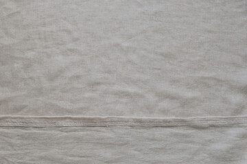 Abstract off-white linen material with garment stitching details. Top view, copy space