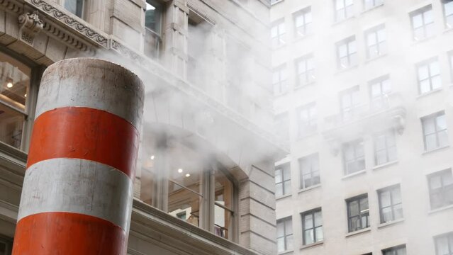 Steam vapor vented on New York City street, orange vapour tube stack. Hot smoke from pipe. Con Edison's Steam Operations system, 5 Fifth avenue, Manhattan Midtown architecture.