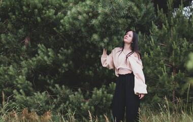 A young girl poses for a photo shoot against the background of pine trees