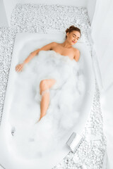 Total relaxation. Young woman enjoying luxurious bath, keeping eyes closed, top view