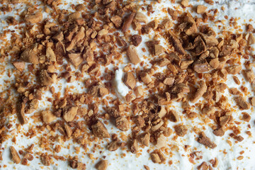 Close-up of a detailed texture of roasted almonds scattered on a background of white, creamy, granular cheese. Food textures.