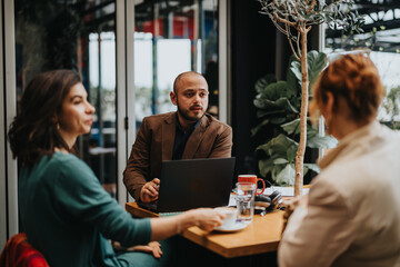 Three business professionals engaged in a discussion with a laptop at a well-lit office space.