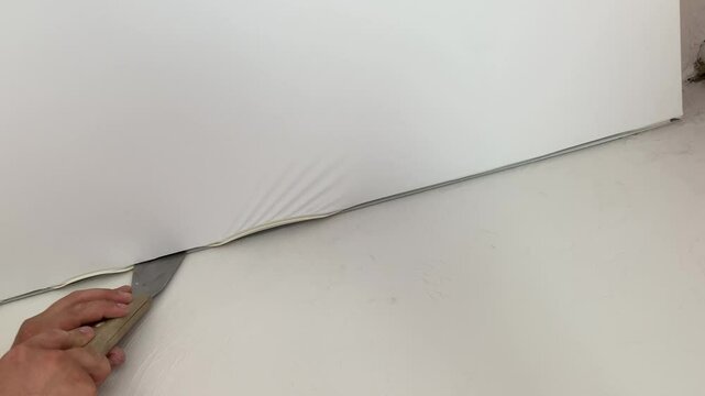 Installation and maintenance of a white stretch ceiling in a new apartment. Apartment construction and renovation
