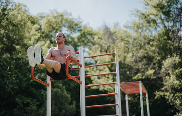 Athletic man performing calisthenics exercises on outdoor park equipment in a sunny urban park setting. Fitness enthusiast practicing strength training.