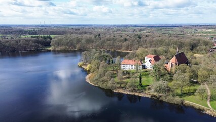 Fototapeta premium Drone view of a small lake in low sun surrounded by fields and woods.