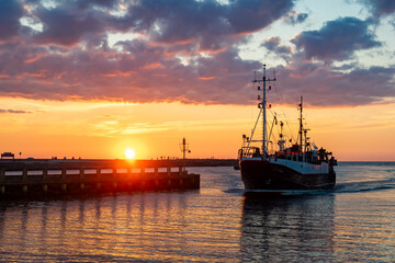 a ship entering the port of Ustka at sunset