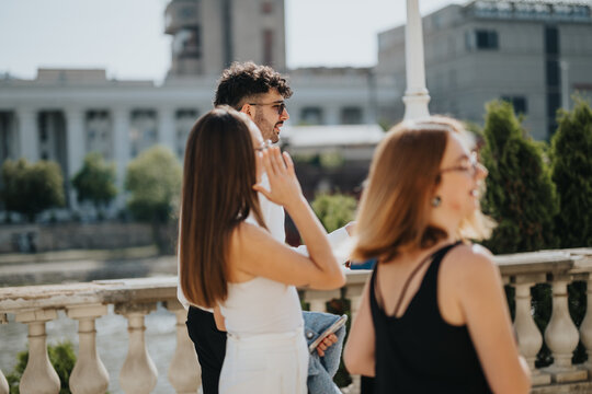 Group of young professionals engaging in a casual outdoor meeting in a city setting, enjoying the sunny day and urban environment.