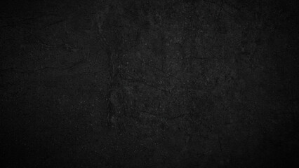 A black wall with a lot of cracks and holes. The wall is made of concrete and has a rough texture
