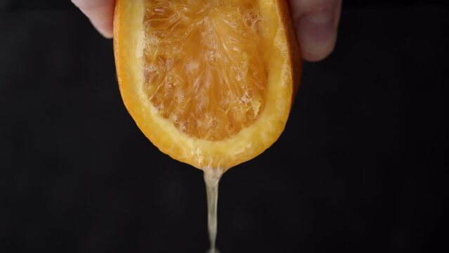 Squeezing orange juice. Close Up on male hand extracting juice from an orange half.