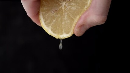 Squeezing lemon juice. Close Up on male hand extracting juice from lemon half.