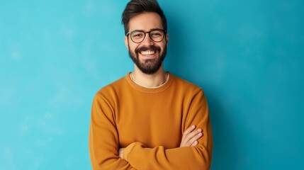 Obraz premium A man with glasses is smiling and wearing a yellow sweater. He is standing in front of a blue wall