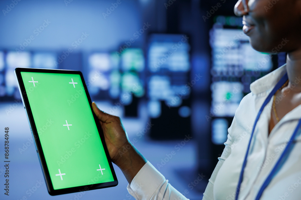 Poster trained technician in server room using mockup tablet to future proof network from downtimes and une