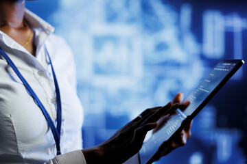 BIPOC computer operator writes code on tablet to visualize artificial intelligence neural networks using augmented reality. High tech workplace executive runs AI script for information processing