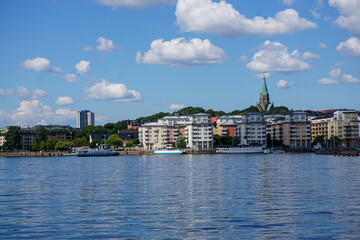 View of buildings by sea against cloudy sky