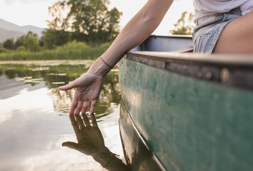Active young woman paddling a canoe on a lake surrounded by green summer nature, close up shot. Canoeing, therapy, and recreation concepts.