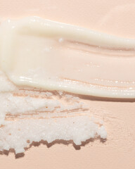 A close-up of a skincare product texture featuring a smooth, creamy moisturizer alongside a granular exfoliant on a soft pink background. Perfect for showcasing beauty routines and cosmetic details in