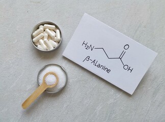 Structural chemical formula of beta-alanine with white pills and beta alanine powder. Beta alanine...
