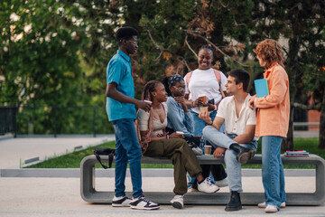 Full length of diverse college students chilling and chatting at campus