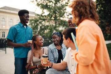 Happy interracial students at campus taking coffee break and talking.