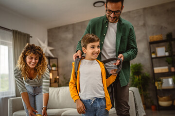 Mum and dad help son to pack snack and backpack for first day school