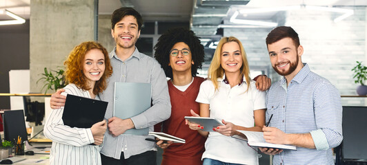 Successful company with happy workers. Cheerful multiethnic team posing at camera, panorama