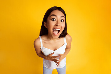 A young Asian woman with long dark hair is wearing a white tank top. She is smiling with her mouth...